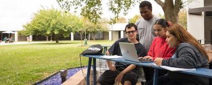 Students review coursework outside at a student lounge area.